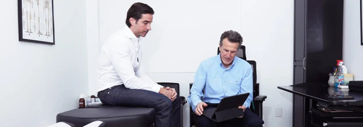 Chiropractor Aspen CO James Bolger Is Going over Health Information with a Male Patient James Bolger Is Going over Health Information with a Male Patient